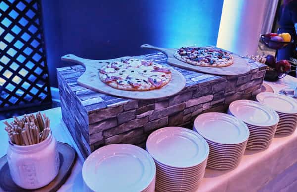 pizzas on board with plates near it