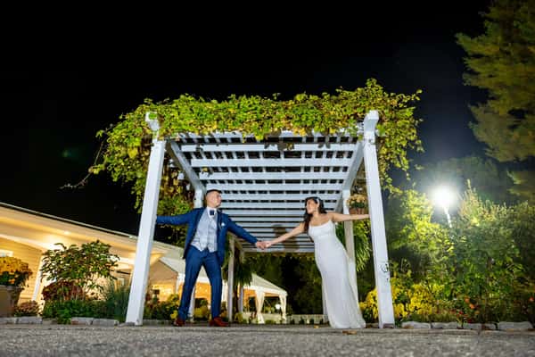 couple holding hands under arch outside