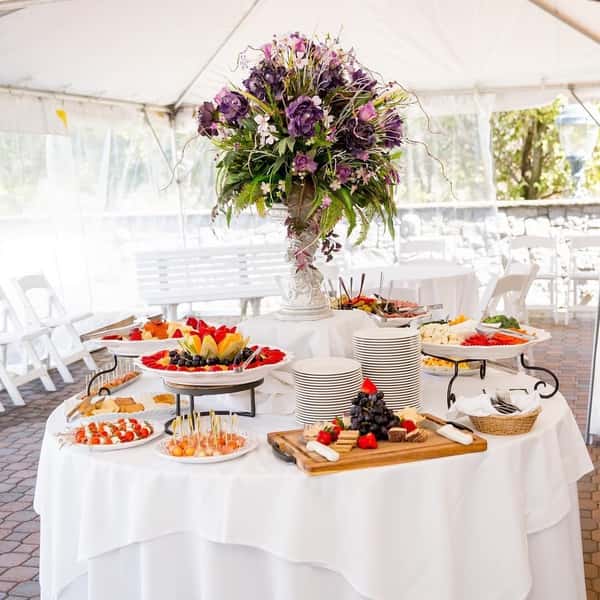 table with assortment of food on platters with floral centerpiece