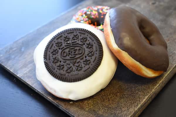 Three varieties of Sweet Donuts, including Oreo, chocolate glazed, and chocolate glazed with sprinkles