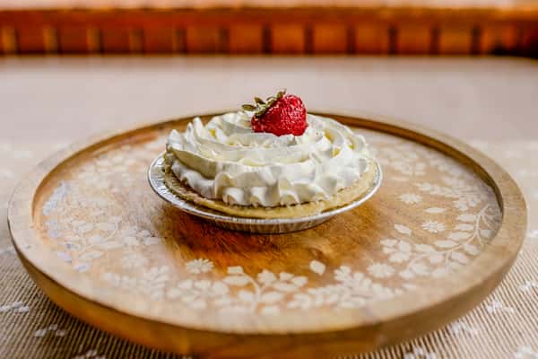 A strawberry pie with whipped cream and a fresh strawberry on top from The Butcher Shop bakery