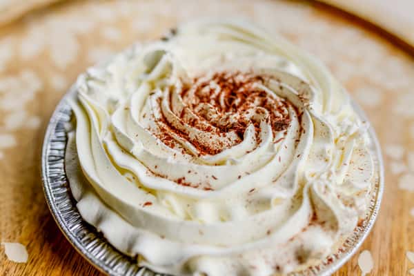 A close-up of a chocolate cream mini pie with decorative whipped cream topping from The Butcher Shop bakery