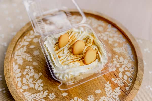 A banana pudding dessert topped with vanilla wafers served in a clear container at The Butcher Shop bakery