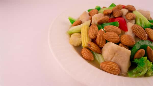 bowl of steamed chicken, broccoli, peppers, onions, baby corn, and almonds