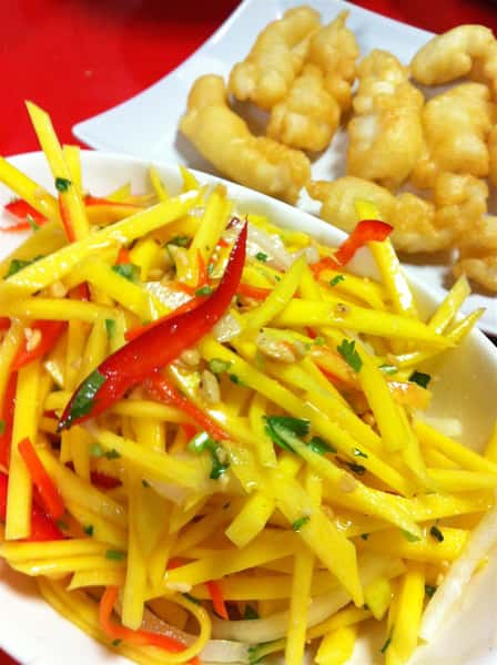 plate of fried chicken tenders, bowl of sliced mango slaw with peppers and cilantro