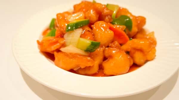 bowl of orange chicken with cucumbers, carrots, and onions
