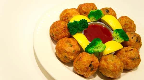 fried rice balls with vegetables, garnished with broccoli and lemon, cup of dipping sauce