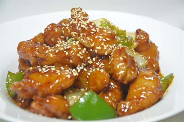 bowl of sesame chicken with bell peppers, onions, and sesame seeds