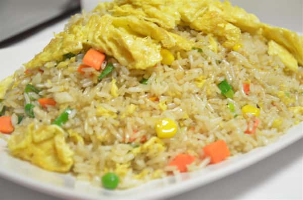 plate of vegetable fried rice, with carrots, peas, peppers, and fried egg