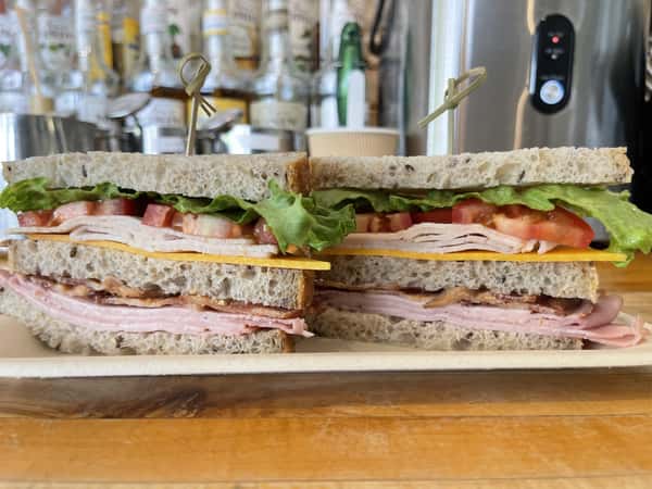 Seeded sourdough bread with Turkey, ham, bacon, Cheddar cheese, roma tomatoes, and lettuce
