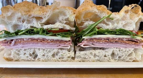 Ham, pepperoni, salami, sopressata, Provolone and herb mozzarella cheese, Arugula, tomato, and herbs vinaigrette on fresh made foccacia