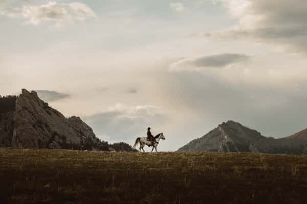 Cowboy riding a horse with a mountain backdrop