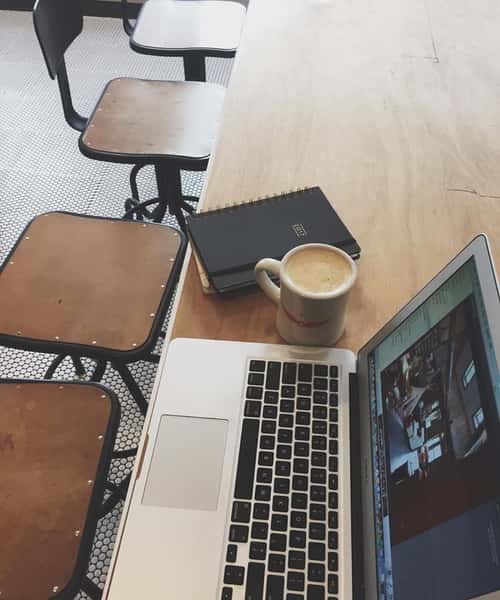 laptop, cup of coffee, and notebook on table at the grind location