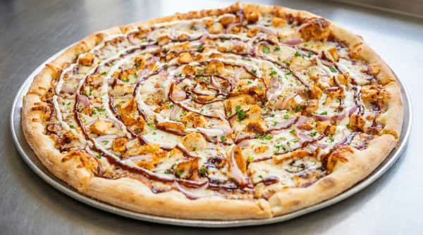 BBQ chicken pizza with melted cheese, red onions, parsley, and a swirl of BBQ and white sauce.