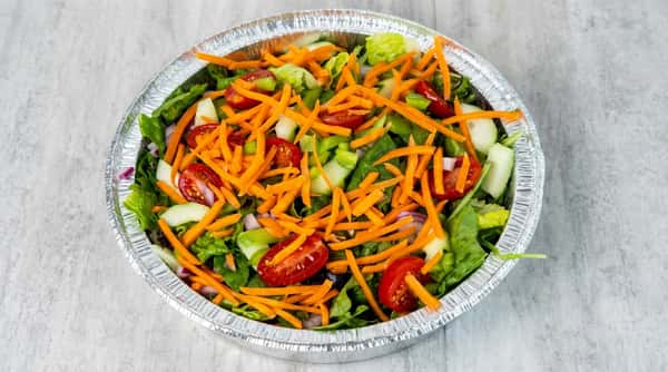 Garden salad in a foil container with lettuce, carrots, tomatoes, cucumbers, bell peppers, and red onion.