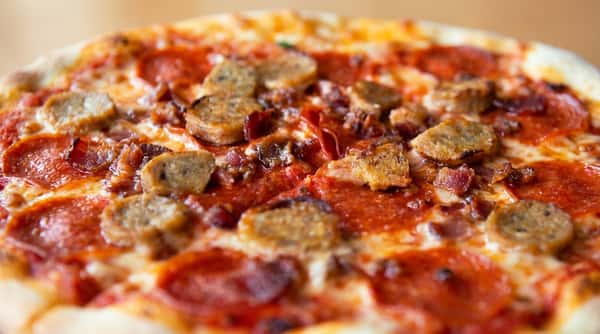Pizza with pepperoni, sausage, and melted cheese, covered in red sauce.