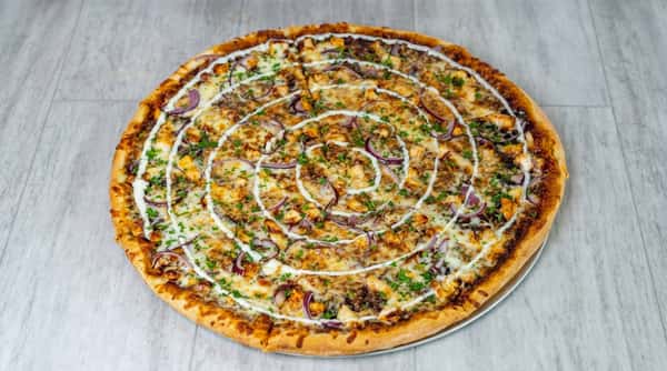 BBQ chicken pizza with red onions, a drizzle of white sauce, and parsley garnish on a light gray surface.