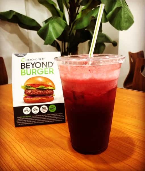 red juice in a to go cup on a table in front of a sign about the Beyond Burger