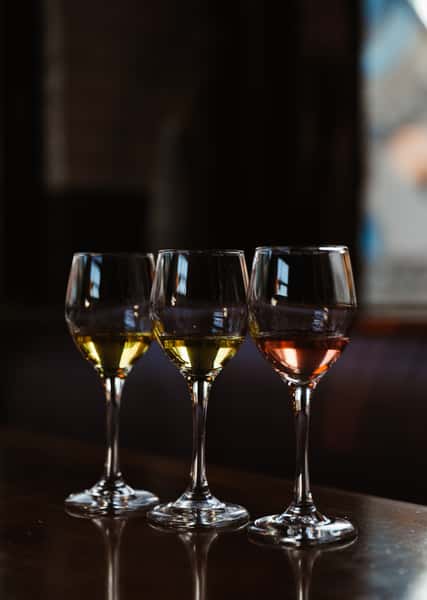 Three wine glasses with varying types of wine