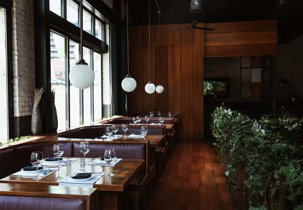 Dark wood walls and floors with booth dining lit by pendant lighting