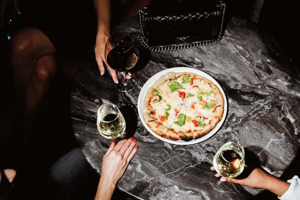 Guests sitting around a black marble table enjoying wine paired with an Italian entree
