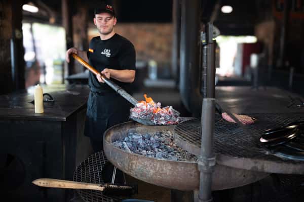 Employee shoveling mesquite coals
