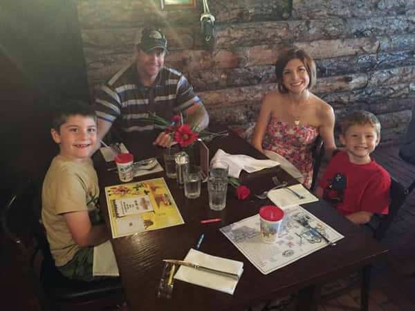 a couple with two young boys sitting at table