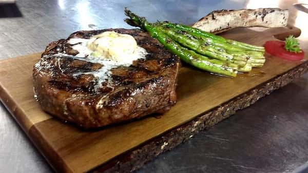 steak topped with butter and a side of asparagus