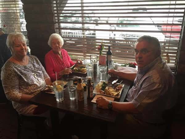 three people sitting at table enjoying a meal