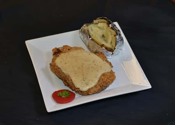 country fried steak topped with gravy with a baked potato