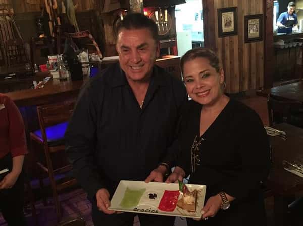 male and female holding a dessert on a plate