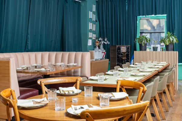 Naturally lit blue interior of restaurant with laid out tables