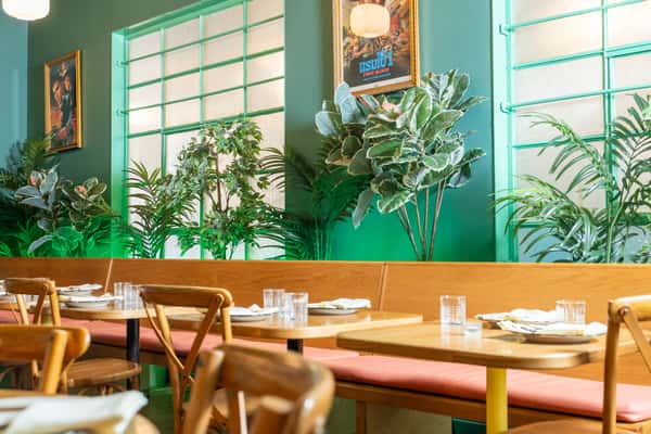 Naturally lit blue interior of restaurant with laid out tables