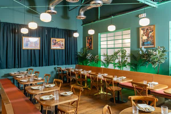 Naturally lit blue interior of restaurant with laid out tables