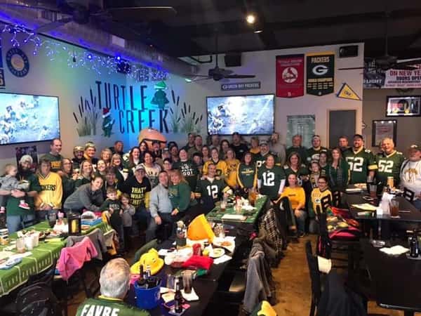 filled dining room crowd with Packers football jerseys for game night