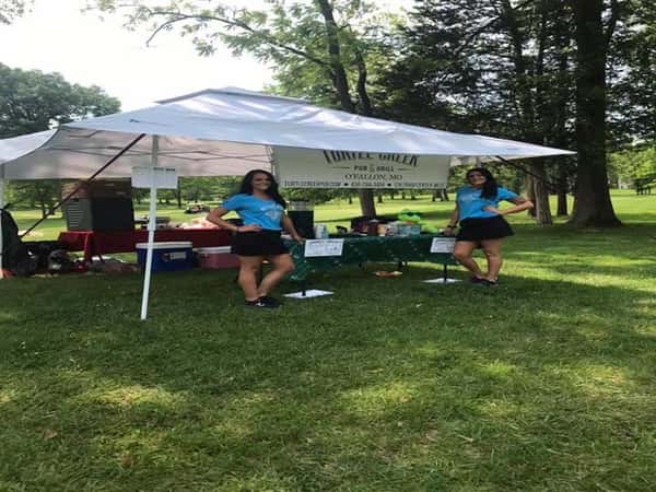two women standing under a tent with turtle creek's logo under it