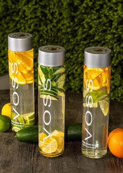 Three VOSS water bottles filled with citrus and cucumber slices for a refreshing, fruit-infused hydration option.