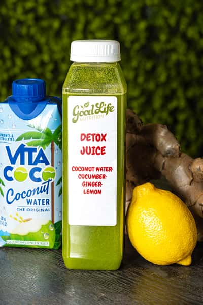 Green detox juice made with coconut water, cucumber, ginger, and lemon, shown with fresh lemon, ginger, and coconut water.