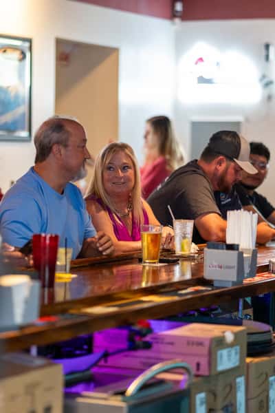Guests enjoying drinks and conversation at the bar inside Parkway Tavern, with a friendly and relaxed sports bar atmosphere featuring draft beers, cocktails, and casual seating.