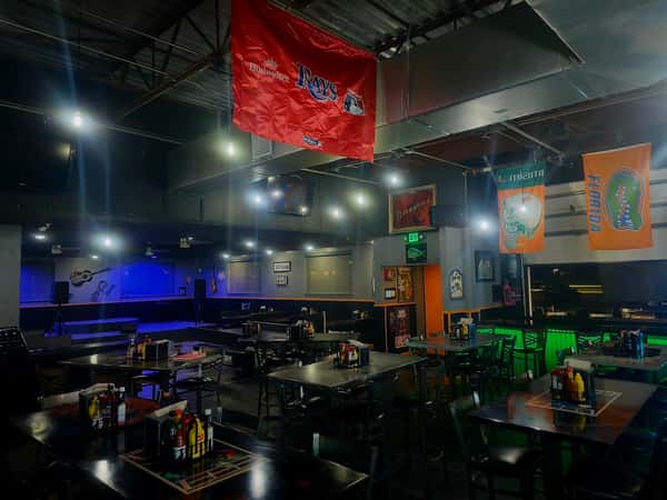 Interior view of a sports bar with flags hanging from the ceiling and neatly arranged tables with condiments.