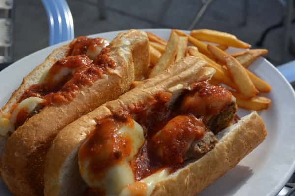 Meatball parmesan sandwich with french fries on the side.