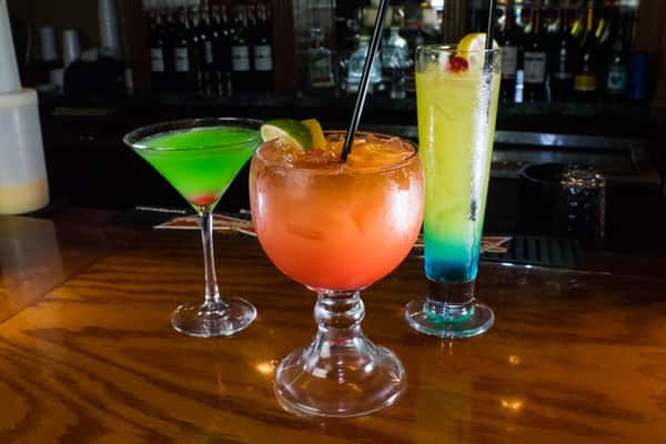 Three colorful cocktails on a bar