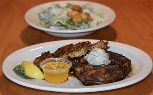 grilled steak topped with garlic butter and grilled shrimp. melted butter on the side with lemon. small caesar salad on the side.
