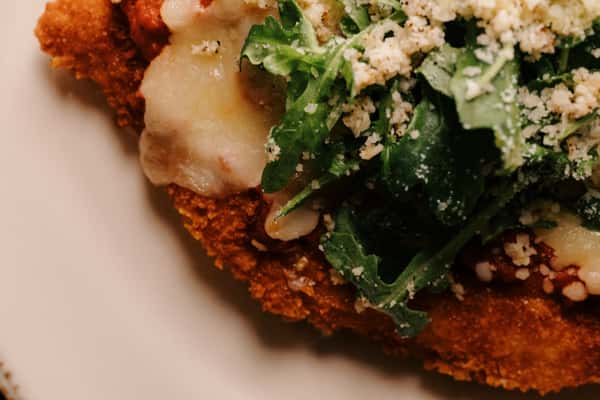 Crispy breaded chicken cutlet topped with melted cheese, arugula, marinara sauce, and grated parmesan.