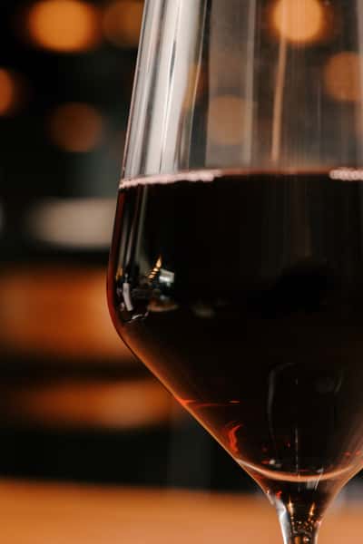 Close-up of a glass of red wine with a softly blurred, warm-toned background evoking an upscale, intimate dining ambiance.