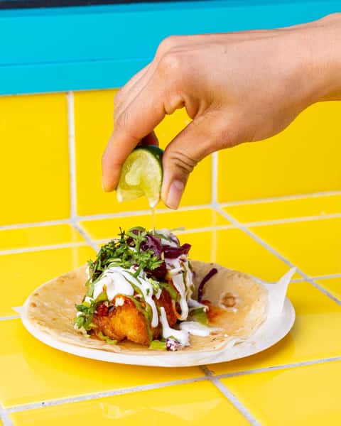 Hand squeezing a lime over a taco