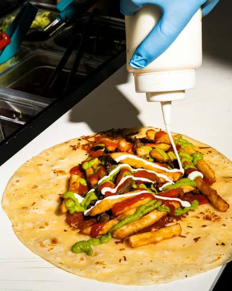Employee drizzling a sauce over a taco