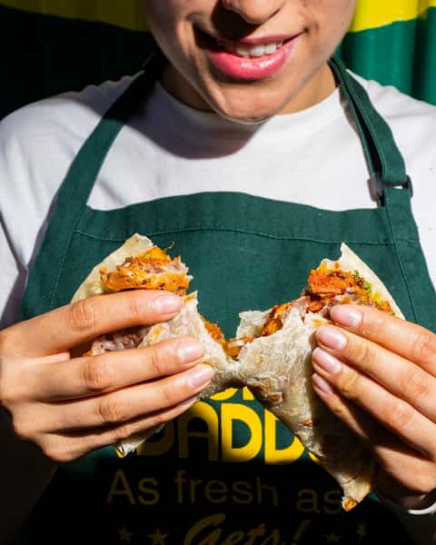 Person holding a burrito cut in half
