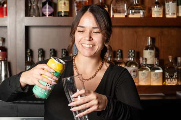 A bartender pouring a beer from a can
