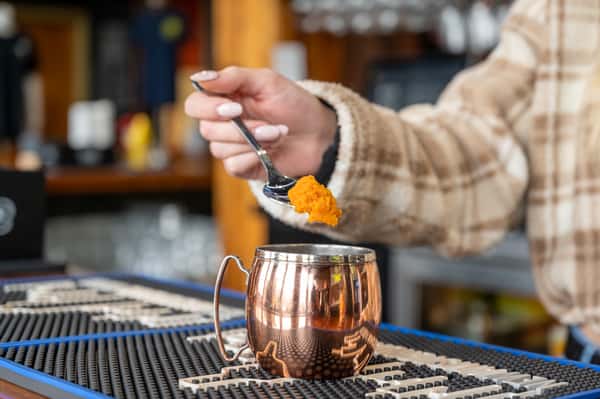 Pumpkin puree being added to a mule cocktail cup